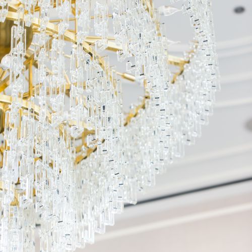 The image shows a close-up of a luxurious, gold and crystal chandelier hanging from a ceiling.